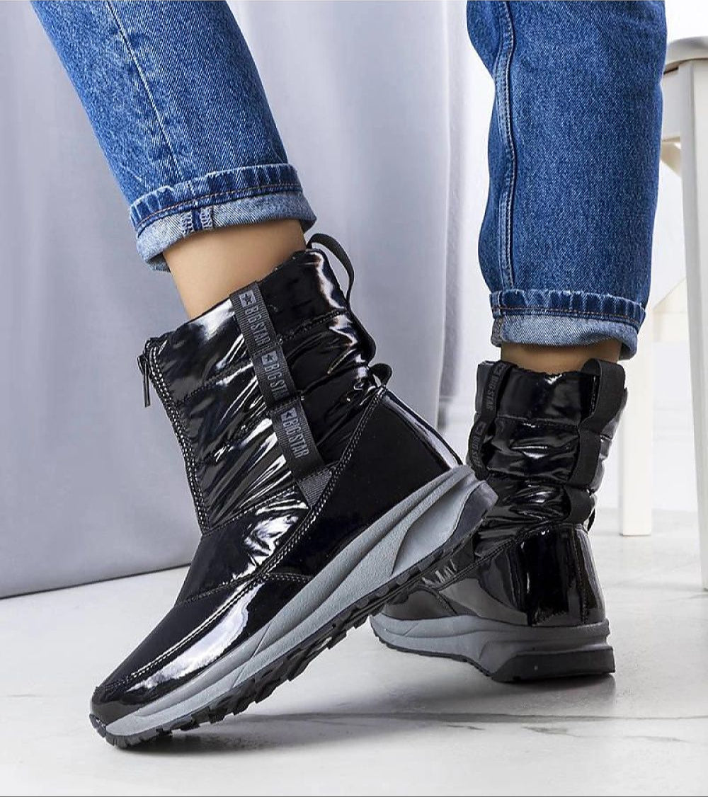 Person wearing black opalescent Orymira insulated platform snow boots with plush fur lining and sleek design in winter setting.