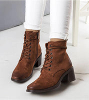 Brown square-toe heeled boots with braided lacing, worn with white jeans, showcasing autumn style and elegant suede-effect finish.