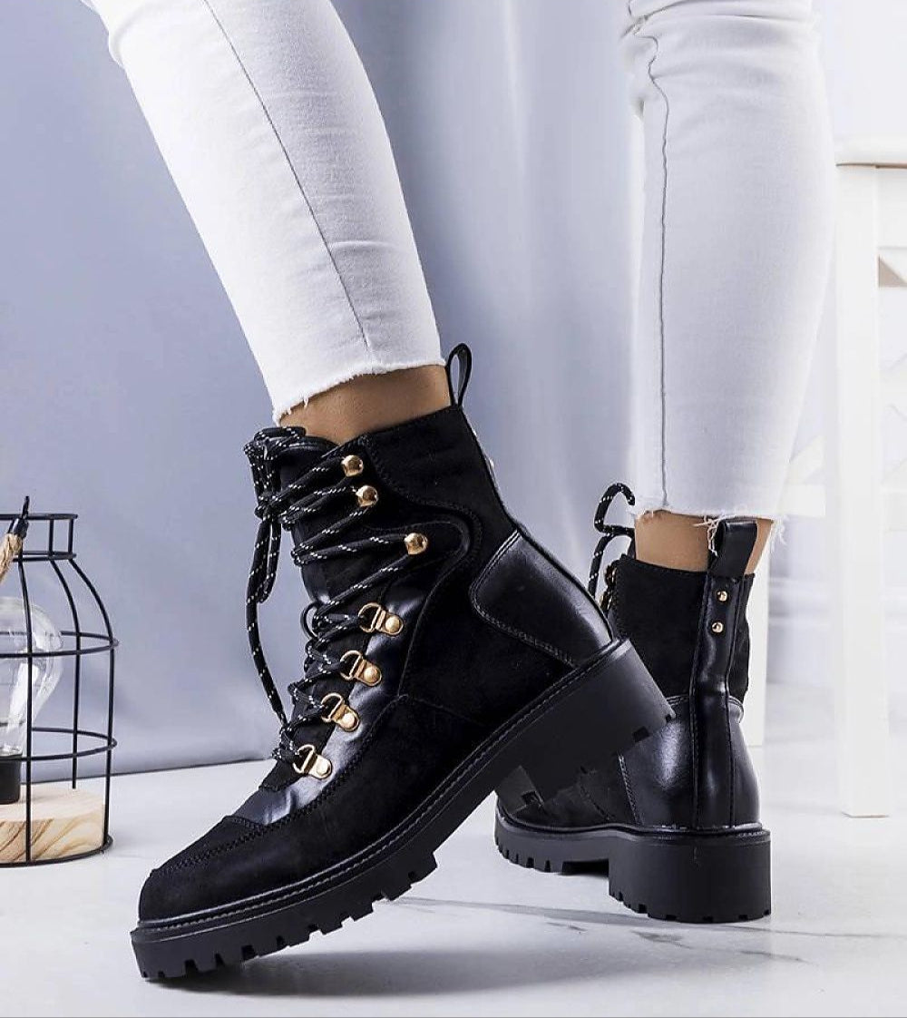 Black insulated lace-up boots with gold-tone details, fur-like lining, worn with white pants, showcasing durable eco leather and suede texture.