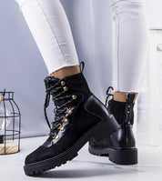Black insulated lace-up boots with gold-tone details, fur-like lining, worn with white pants, showcasing durable eco leather and suede texture.