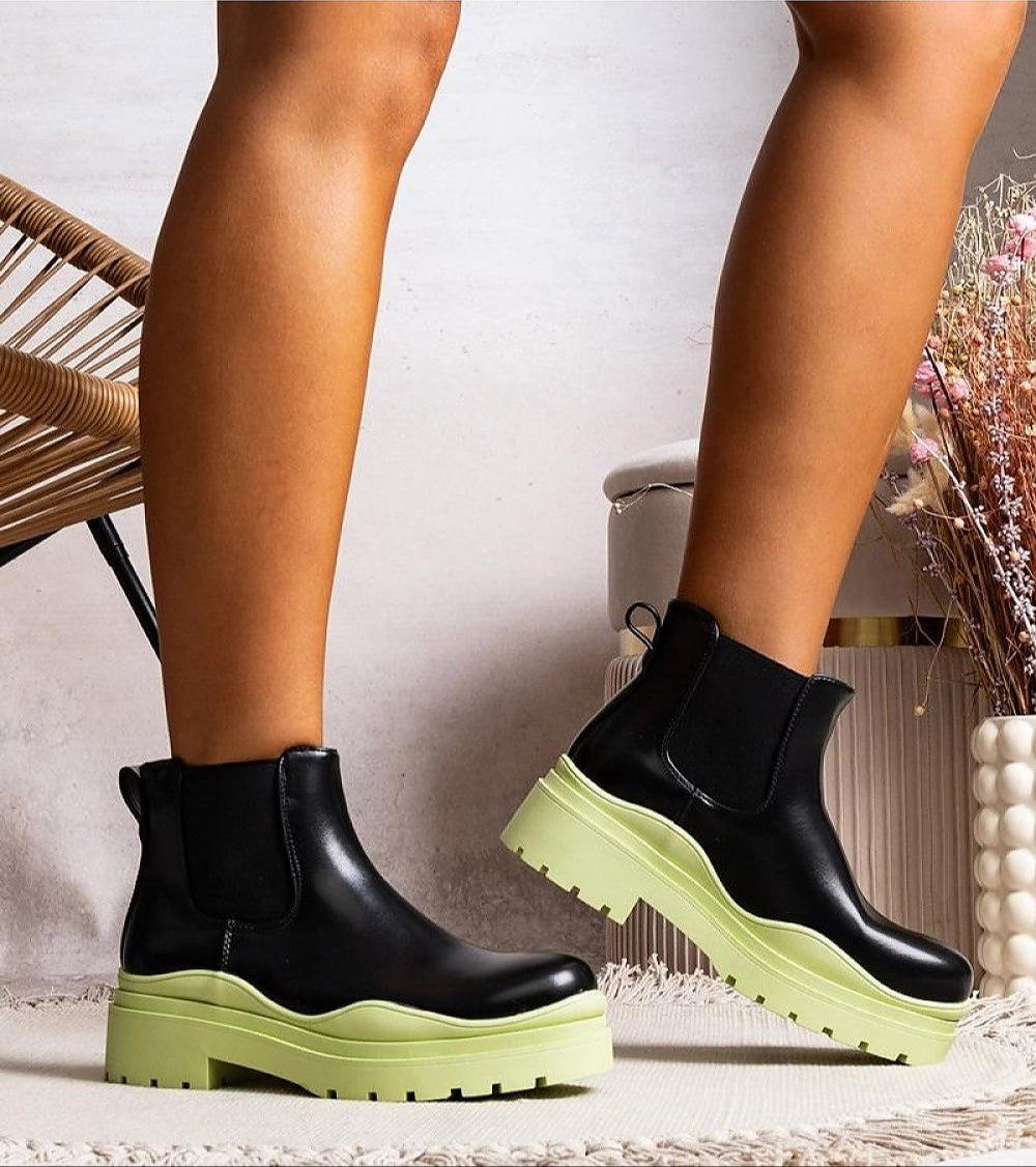 Tharelle slip-on ankle boots in vegan leather with rugged trapper soles, shown in a modern setting for transitional weather fashion.