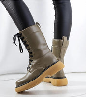Draxira lace-up combat boots in matte eco leather with thick rubber sole, styled with black leggings for urban streetwear appeal.