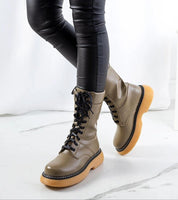 Green lace-up combat boots with thick rubber soles and matte finish, perfect for urban and rock-inspired outfits.
