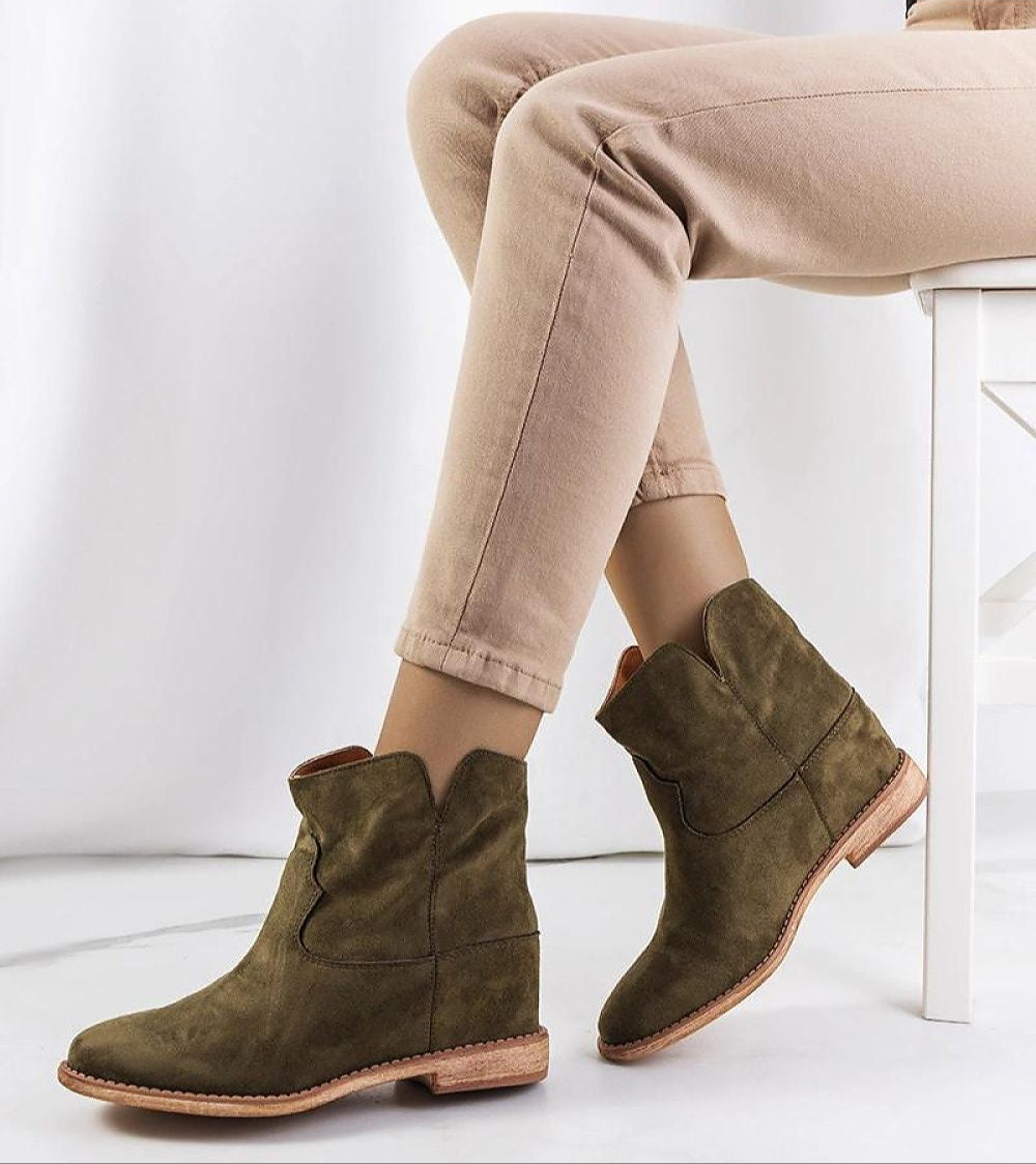 Woman wearing khaki ankle boots with jeans, sitting on a chair. Fashionable footwear for autumn with sculpted silhouette and cozy design.