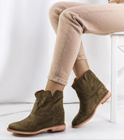 Woman wearing khaki ankle boots with jeans, sitting on a chair. Fashionable footwear for autumn with sculpted silhouette and cozy design.