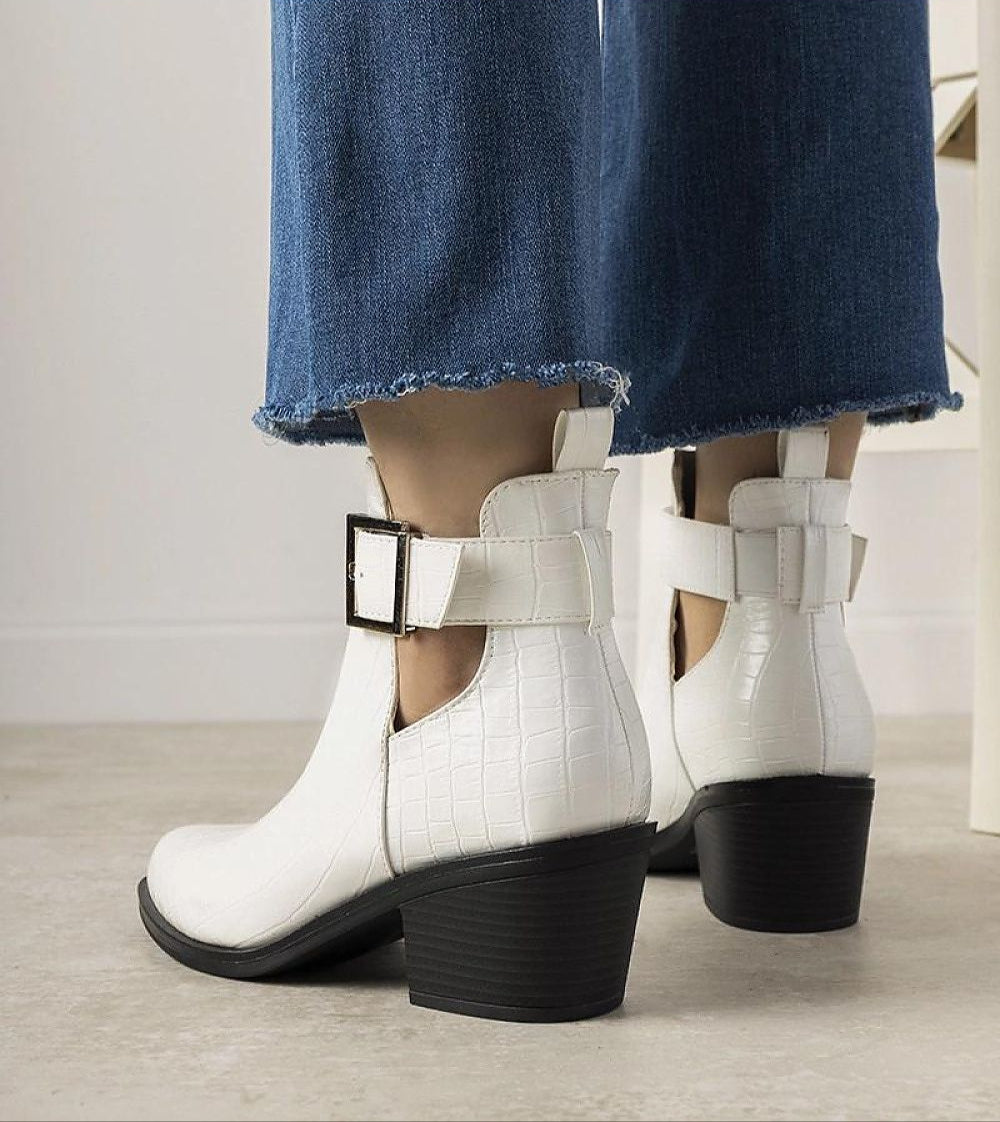 White Alvarine cut-out ankle boots in crocodile-effect eco leather with black block heel, worn with jeans, showcasing adjustable strap.