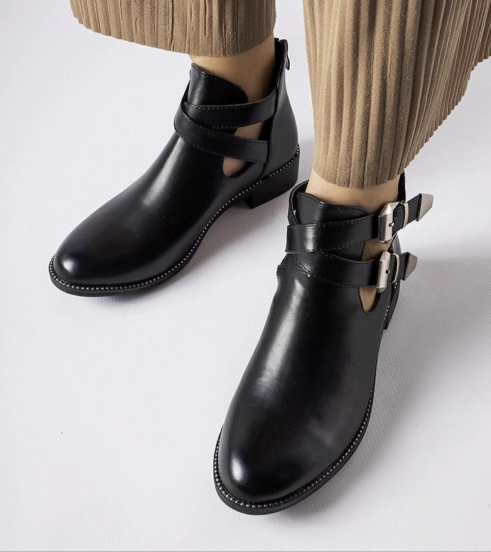 Dravelle cut-out ankle boots with side buckles, black eco leather, paired with pleated trousers, showcasing stylish and edgy footwear.