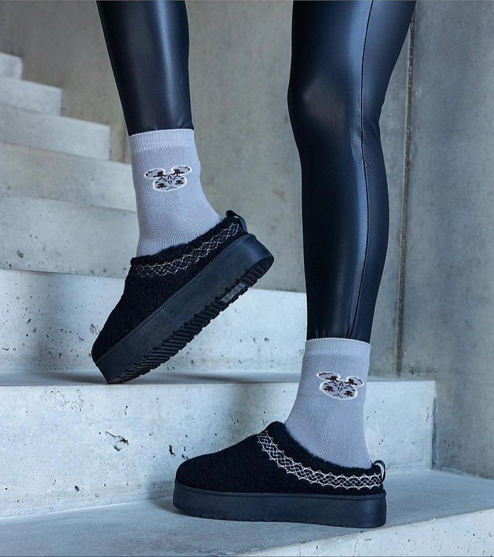 Person wearing Tavelya Embroidered Winter Snow Boots in black with cozy socks, standing on stone steps.