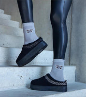 Person wearing Tavelya Embroidered Winter Snow Boots in black with cozy socks, standing on stone steps.
