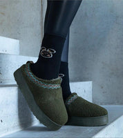 Person wearing green embroidered winter snow boots on concrete stairs