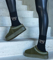 Person wearing Tavelya Embroidered Winter Snow Boots with green exterior and embroidered detailing, stepping on stairs indoors.