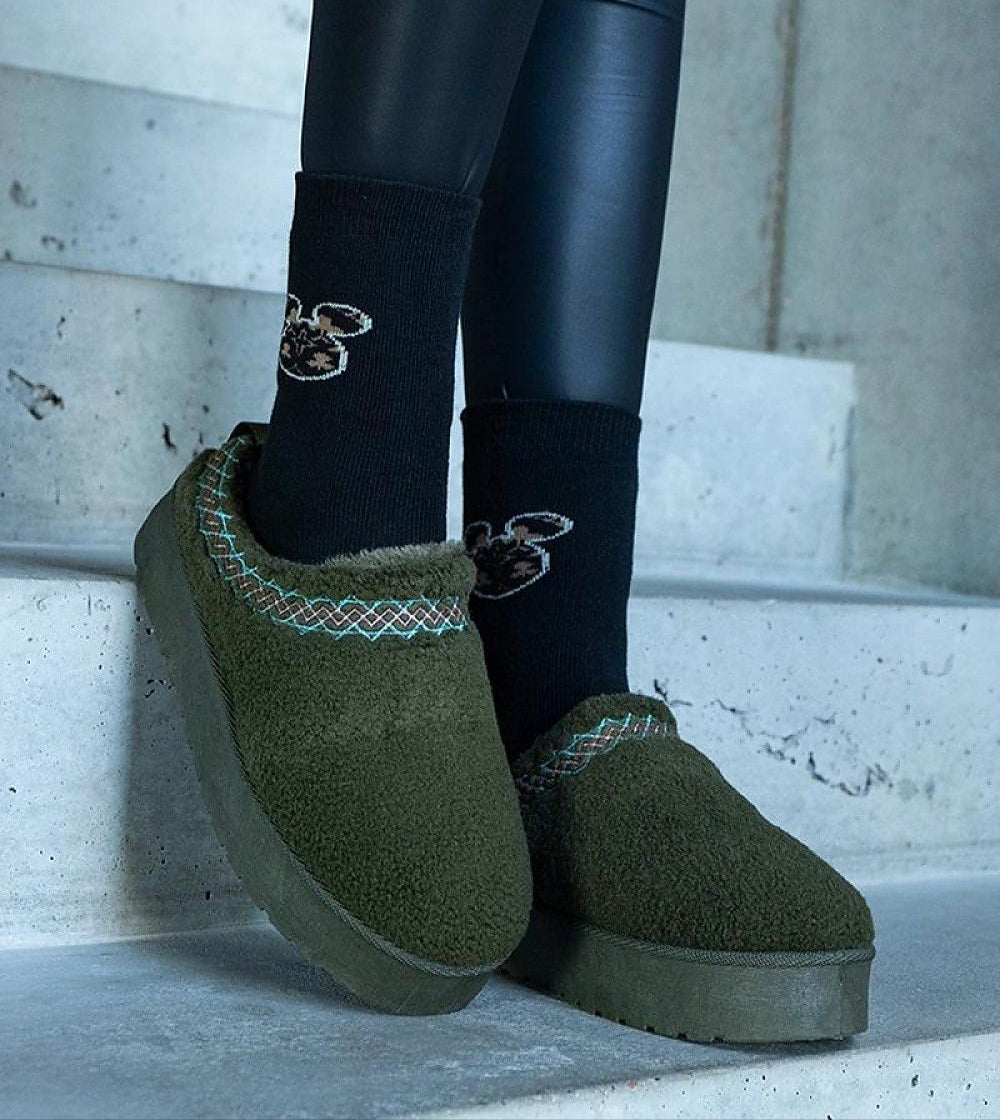 Person wearing Tavelya Embroidered Winter Snow Boots with green fabric and black socks, showcasing cozy winter fashion on stairs.