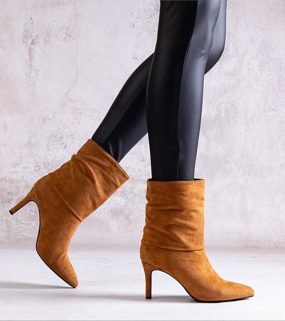 Narelle stiletto heel boots in tan, featuring a sculpted heel and suede-look texture, worn with black leggings on a textured backdrop.