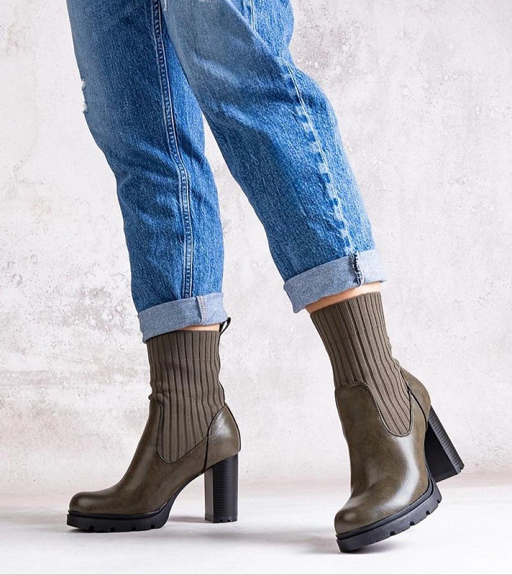 Person wearing Nuvarelle Stiletto Ankle Boots with jeans, showcasing the olive hue, 9 cm heel, and ribbed sock design for autumn style.