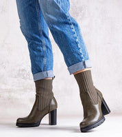 Person wearing Nuvarelle Stiletto Ankle Boots with jeans, showcasing the olive hue, 9 cm heel, and ribbed sock design for autumn style.