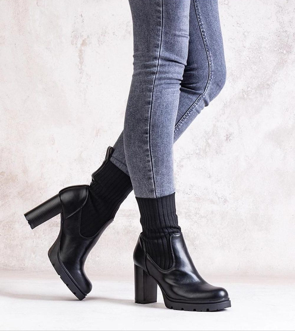 Woman wearing Nuvarelle Stiletto Ankle Boots with black socks and gray jeans, showcasing elegant footwear for autumn fashion.