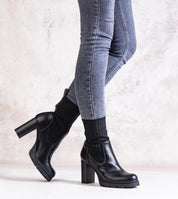 Woman wearing Nuvarelle Stiletto Ankle Boots with black socks and gray jeans, showcasing elegant footwear for autumn fashion.