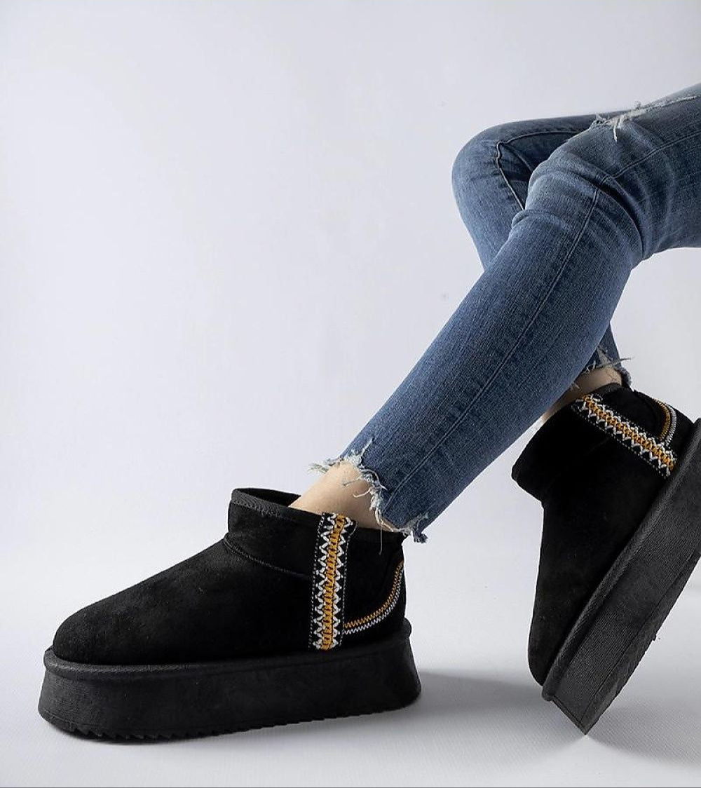Person wearing Orvanna insulated platform snow boots in black with blue jeans, showcasing eco leather material and platform design.