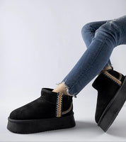 Person wearing Orvanna insulated platform snow boots in black with blue jeans, showcasing eco leather material and platform design.