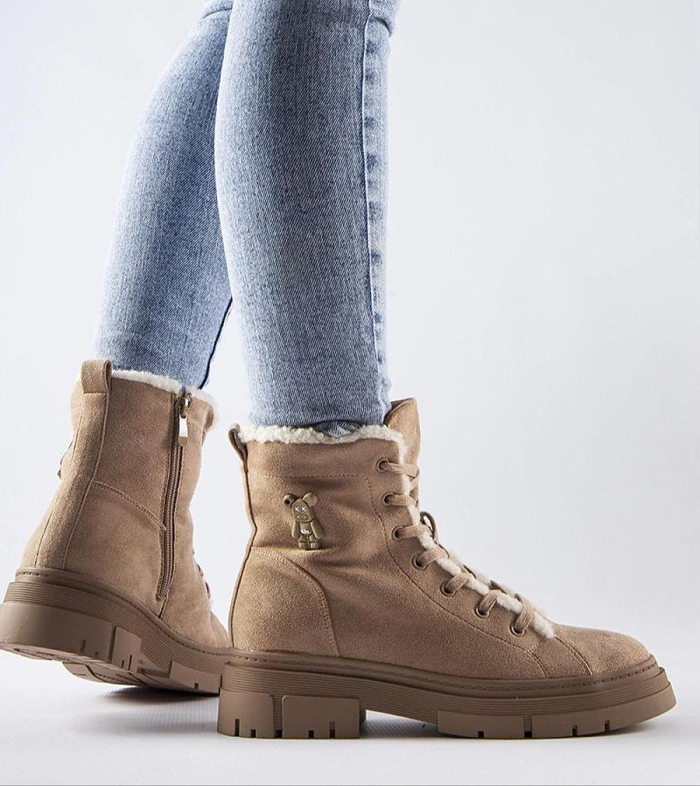 Woman wearing Pombera suede platform boots with side zipper in a light tan color, paired with blue jeans, showcasing winter fashion.