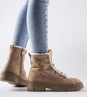 Woman wearing Pombera suede platform boots with side zipper in a light tan color, paired with blue jeans, showcasing winter fashion.
