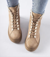 Beige suede platform boots with white fur lining and side zipper, perfect for winter wear, paired with blue jeans.