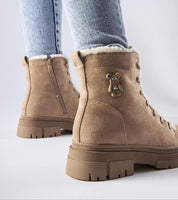 Tan suede platform boots with teddy bear charm, side zipper, and furry lining, worn with light denim jeans on a white background.