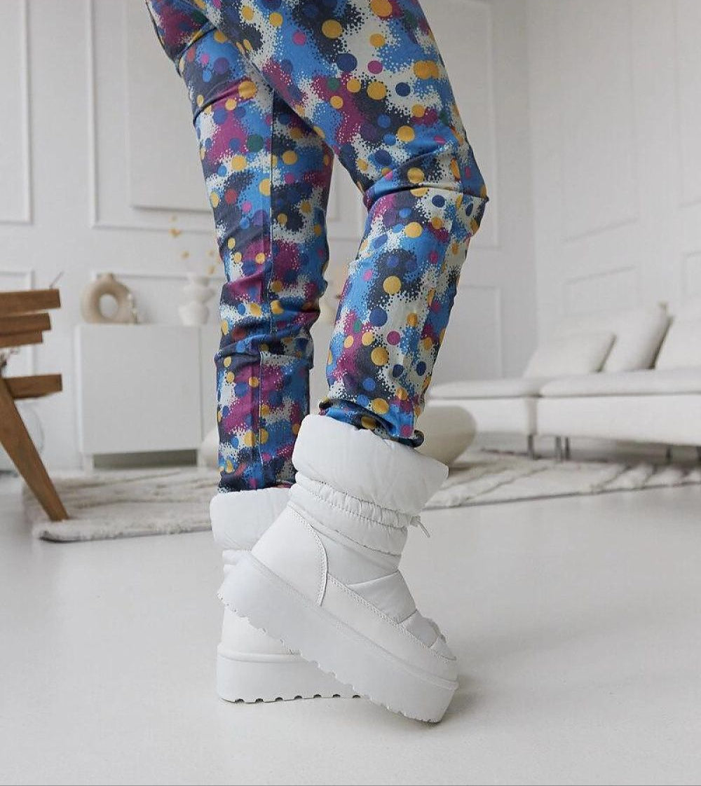 Person wearing Olviera slip-on platform snow boots inside stylish room, showcasing bold design and 5 cm platform.