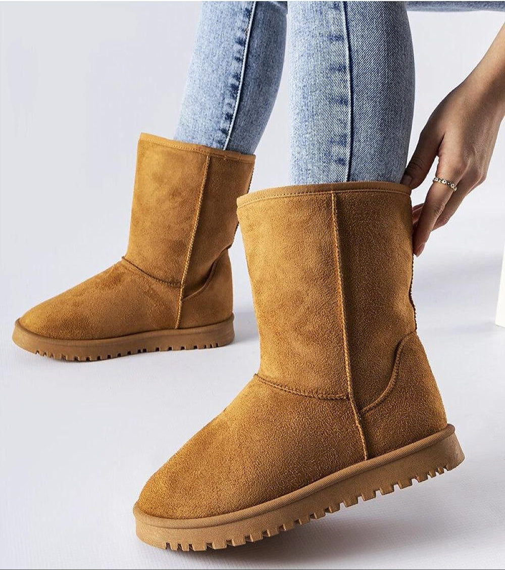 Person wearing Arlosa insulated slip-on snow boots in tan, demonstrating stylish ankle-high design and grip sole on jeans background