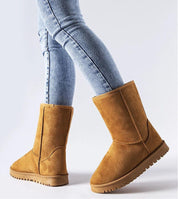 Person wearing Arlosa insulated slip-on snow boots in brown, showcasing winter fashion with jeans on a light background.