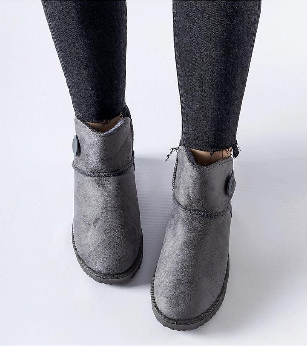 Person wearing Narevik Slip-On Winter Snow Boots with jeans, showcasing the grey ankle-high design and durable water-resistant fabric.