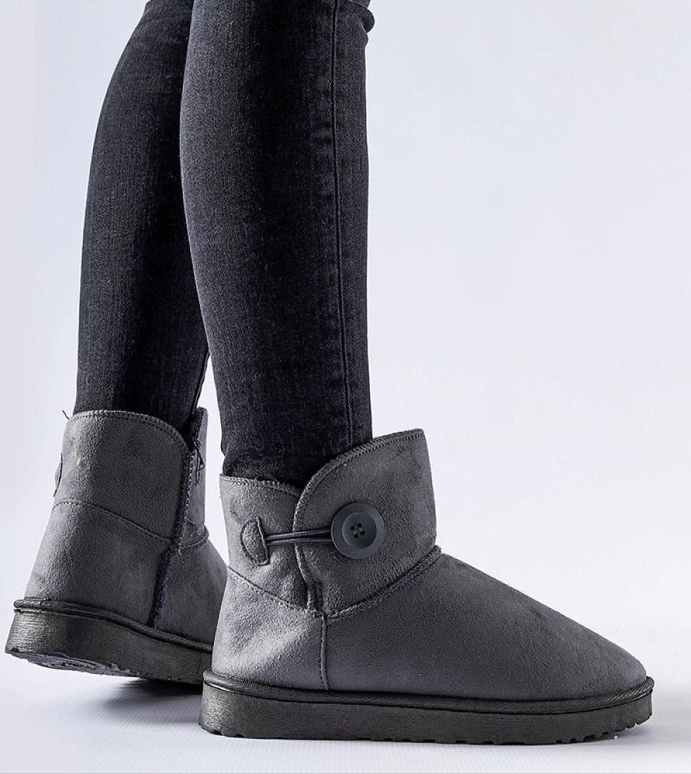 Person wearing Narevik Slip-On Winter Snow Boots, featuring ankle-high silhouette and button detail, ideal for cold, snowy days.
