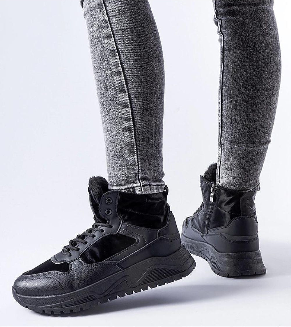 Person wearing Tharmin Winter Lace-Up Sneakers in black with gray jeans, highlighting high-top design and durable rubber sole for winter.