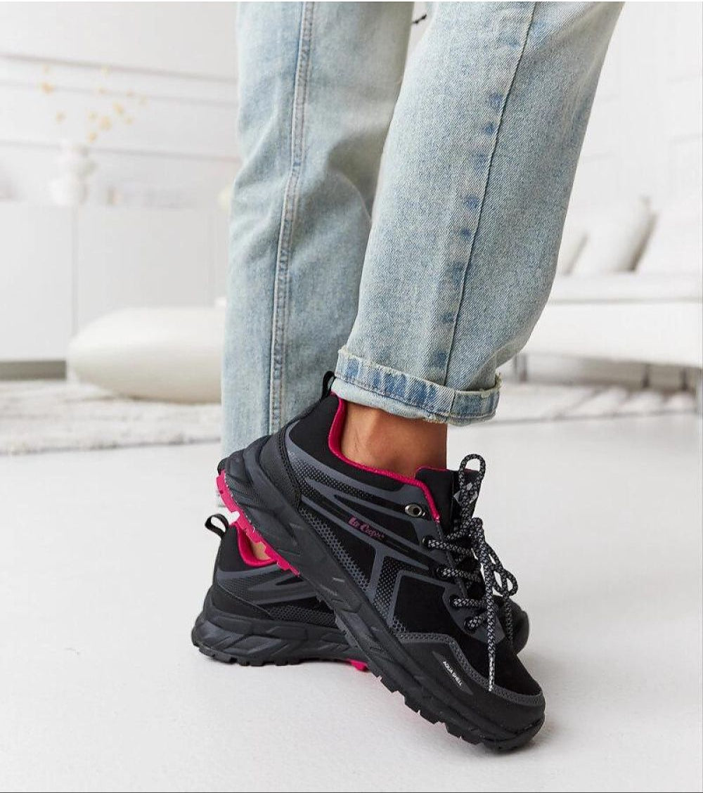 Black and pink insulated winter sneakers on person wearing jeans, showcasing comfort and style for cold weather.