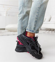 Black and pink insulated winter sneakers on person wearing jeans, showcasing comfort and style for cold weather.