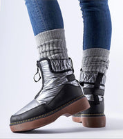 Person wearing Zandara Waterproof Winter Boots, silver and black design for snow, with side zipper and flat heel on urban pavement.
