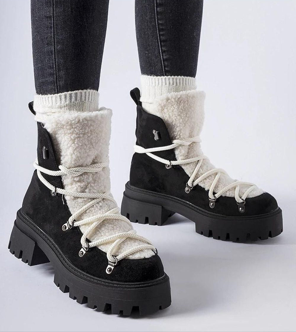 Person wearing Perivana Lace-Up Winter Baggers, black ankle-high boots with white lace, round toe, eco leather, warm lining, rubber sole.