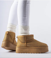 Brown snow boots with zircon embellishments, featuring platform sole and ankle-length cut, worn by model in white pants.