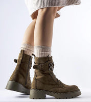 Person wearing Castore green suede platform boots with side zipper and elevated sole, showcasing winter fashion and practicality.