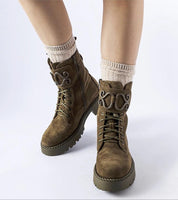Green suede platform boots with eco-friendly design, featuring side zippers and laces for adjustable fit, worn with cozy socks.