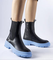 Black ankle boots with blue soles and side zippers, showcasing modern style and practical design.
