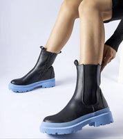 Person wearing Vereliane ankle boots with vegan leather upper and blue rubber soles, showcasing modern style and functionality.