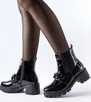 Velandra Glossy Buckle Boots in black patent-effect eco leather with metal buckle and side zipper on model's feet.