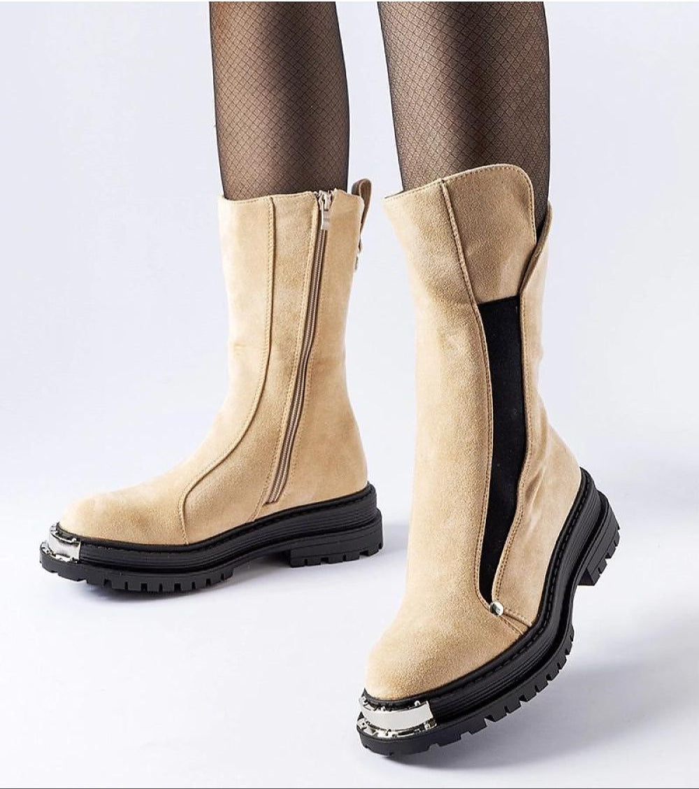 Beige mid-heel boots with side zipper and decorative sole, worn with black fishnet stockings, showcasing stylish winter footwear.