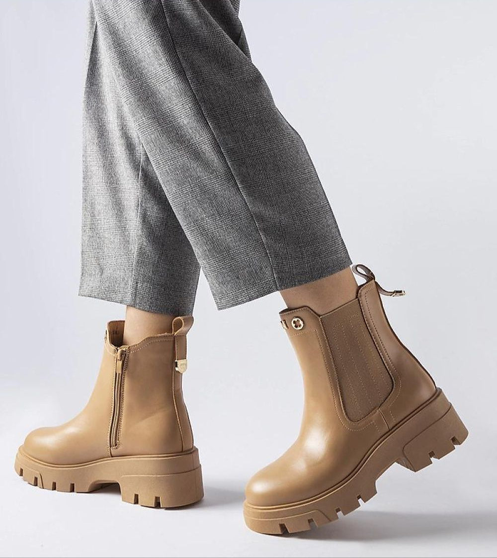 Chic Medanira platform insulated boots in tan with side zipper, offering style and warmth, paired with gray pants for a winter-ready look.