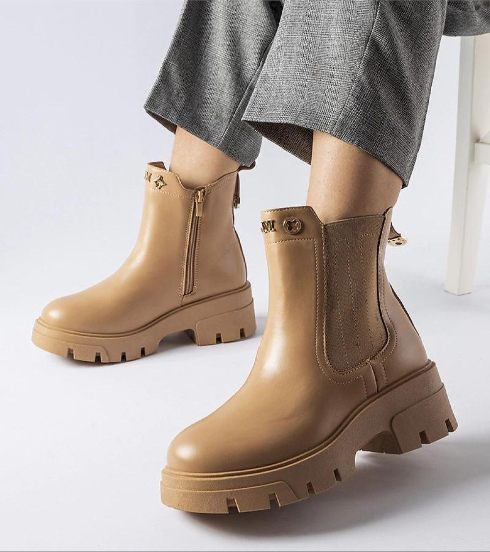 Tan platform insulated ankle boots with side zipper and chunky sole paired with gray pants, showcasing chic design and cold-weather comfort.