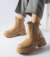 Tan platform insulated ankle boots with side zipper and chunky sole paired with gray pants, showcasing chic design and cold-weather comfort.