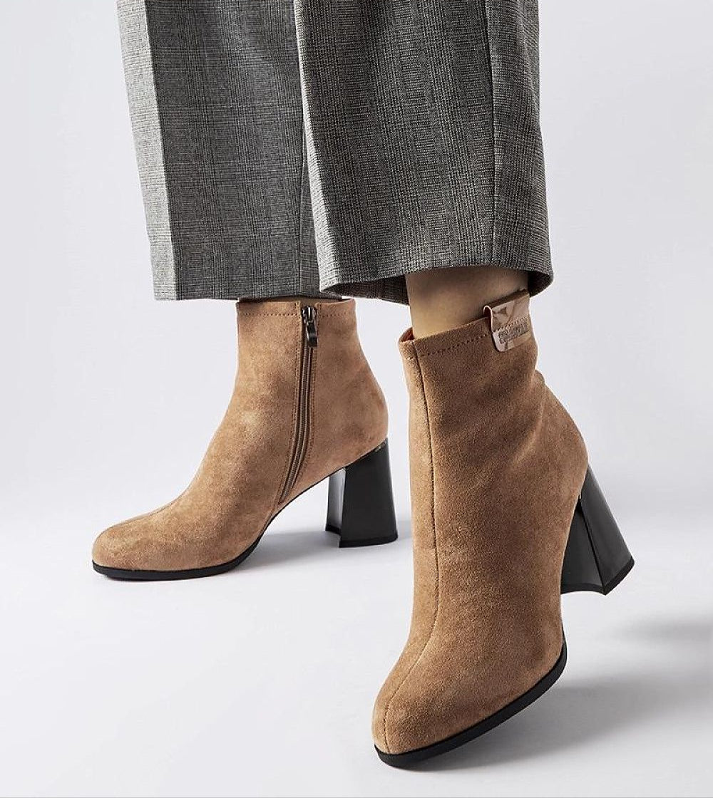 Stylish brown suede ankle boots with block heels and side zipper, paired with gray trousers, perfect for winter fashion.