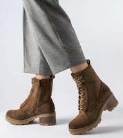 Model wearing Clementina Block-Heel Winter Boots in brown eco leather with side zipper and laces, paired with gray pants.