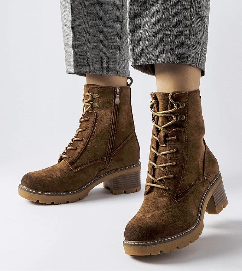 Woman wearing brown Clementina block-heel winter boots with laces and side zipper, showcasing comfort and style.